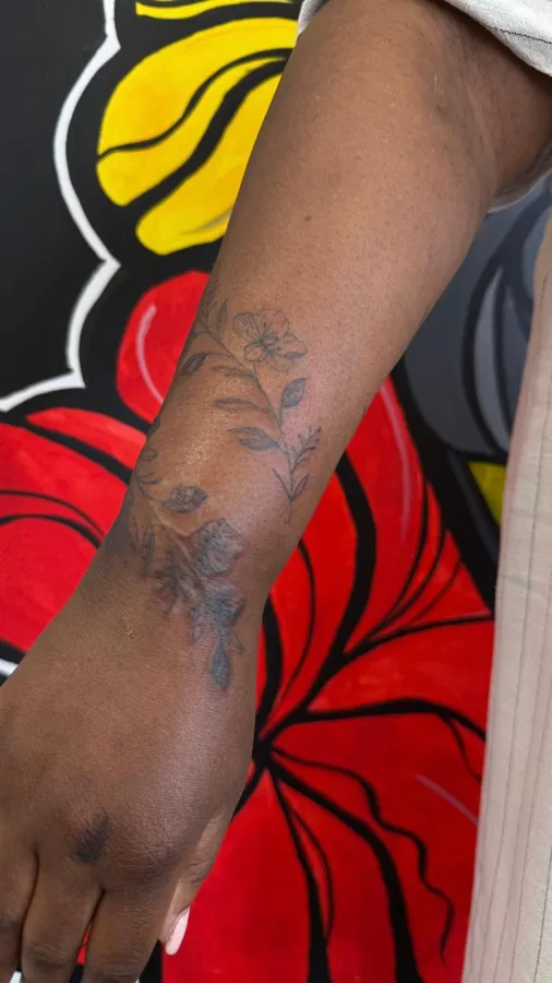 Fine-line floral tattoo on forearm